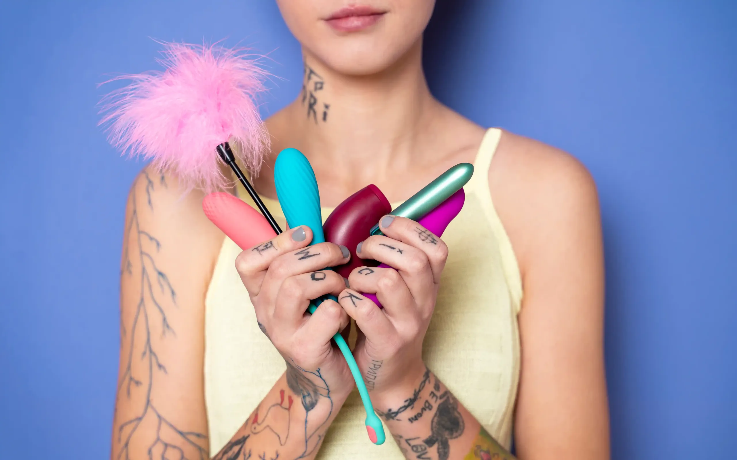 Female model holding a collection of sex toys in her hands